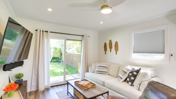 A living room with a sofa, coffee table, TV, and a sliding glass door leading to a backyard. - Three Oaks Home w/ Guest House - 8 Mi to Beach! (Three Oaks)