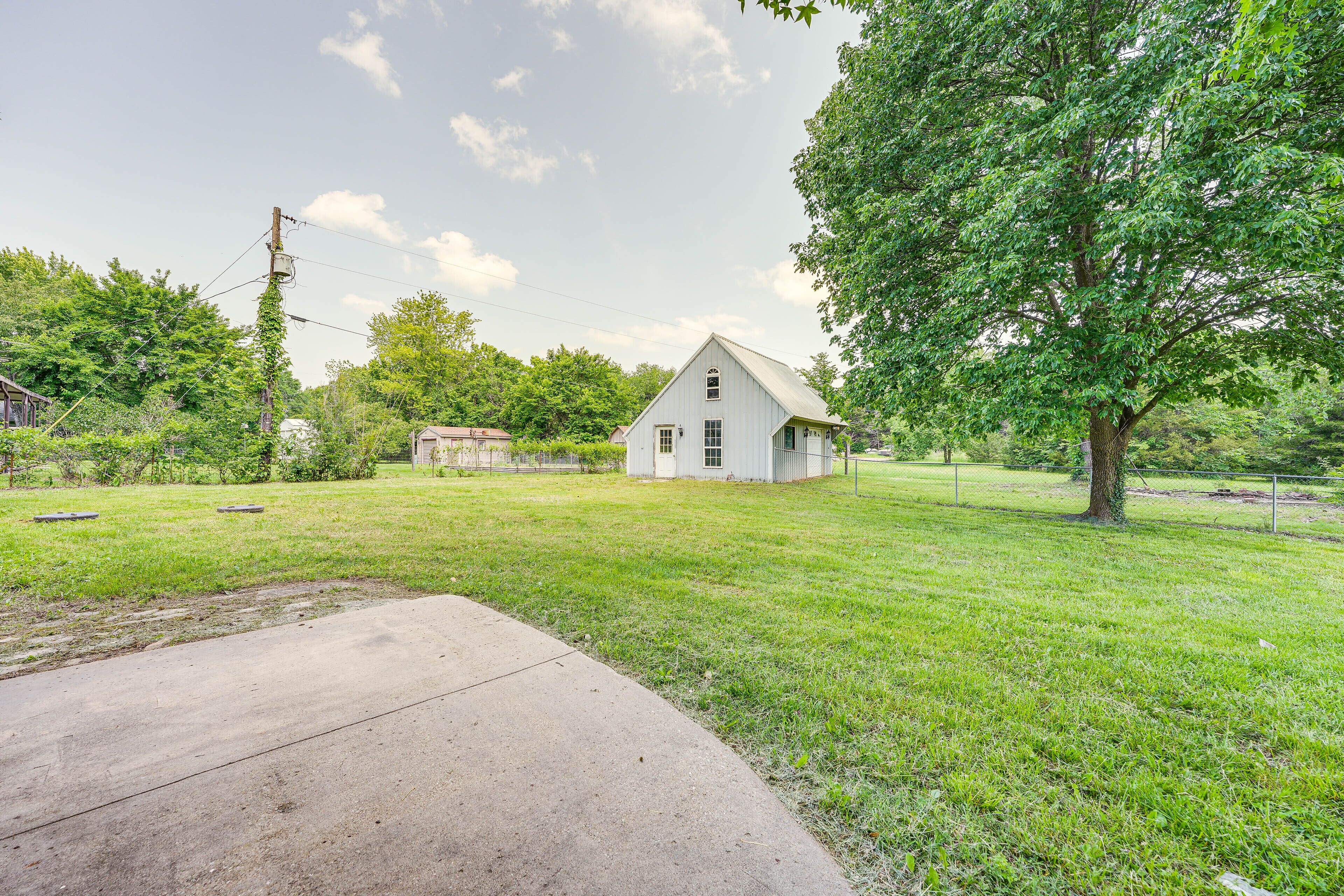 A grassy yard with a white house, a tree, and a concrete path.