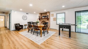 Un coin repas avec une table et des chaises en bois, une cheminée et une table de baby-foot.