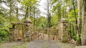 A rustic wooden gate with stone pillars and a stone archway, leading into a forested area. - Secluded Elka Park Cabin: Hot Tub & Fire Pit! (Tannersville)