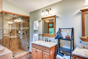 A bathroom with a glass shower enclosure, a vanity with a sink, and a mirror above the vanity.