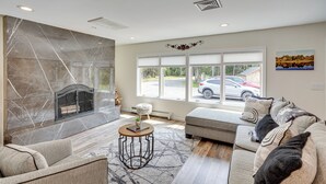A spacious living room with a fireplace, a large window, and a cozy seating area. - 6 Mi to Hunter Mtn: Winter Retreat w/ Hot Tub! (Tannersville)