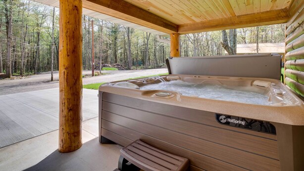 A hot tub with a wooden exterior and a view of a forested area. - Hatfield Vacation Rental w/ Private Hot Tub! (Merrillan)