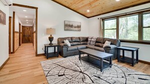 A modern living room with a wooden ceiling, a large window, and a cozy sofa. - Hatfield Vacation Rental w/ Private Hot Tub! (Merrillan)