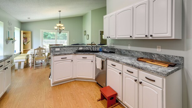 A kitchen with white cabinets, a granite countertop, and a wooden stool. - Swansboro Vacation Rental, 4 Mi to Hammocks Beach! (Swansboro)