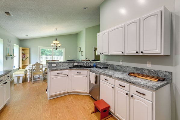 A kitchen with white cabinets, a granite countertop, and a wooden bench.