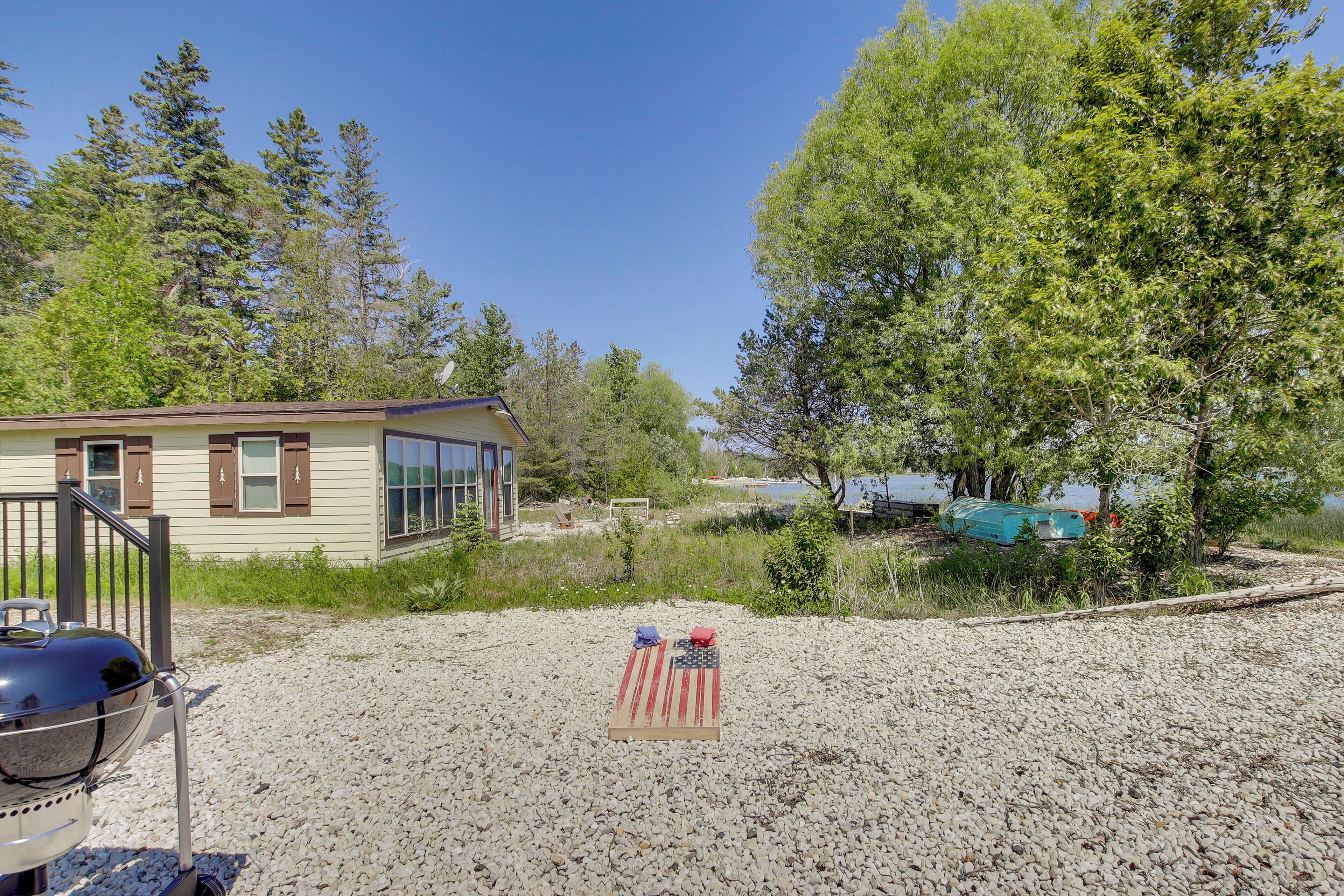 A house with a gravel yard, a grill, and a flag.