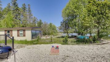 A house with a gravel yard, a grill, and a flag.