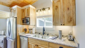 Une cuisine moderne avec des meubles en bois, des appareils électroménagers en acier inoxydable et un plan de travail en marbre.