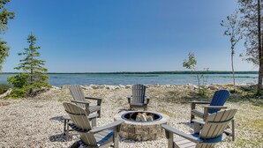 Un espace aménagé au bord du lac, avec des fauteuils Adirondack et un foyer.