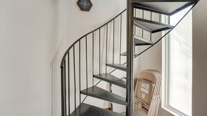 Una escalera de caracol con barandillas de metal y una ventana a la derecha.