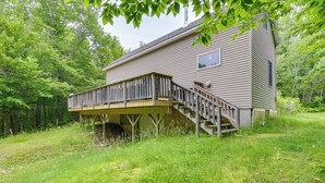 Une maison en bois avec une terrasse et un escalier menant à un espace abrité.