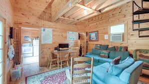 L’intérieur d’une cabane en bois comprend un coin repas, un canapé et un bureau avec un ordinateur.