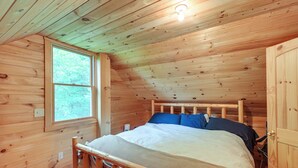 Une chambre dans une cabane en bois, avec un lit, une fenêtre et une porte.