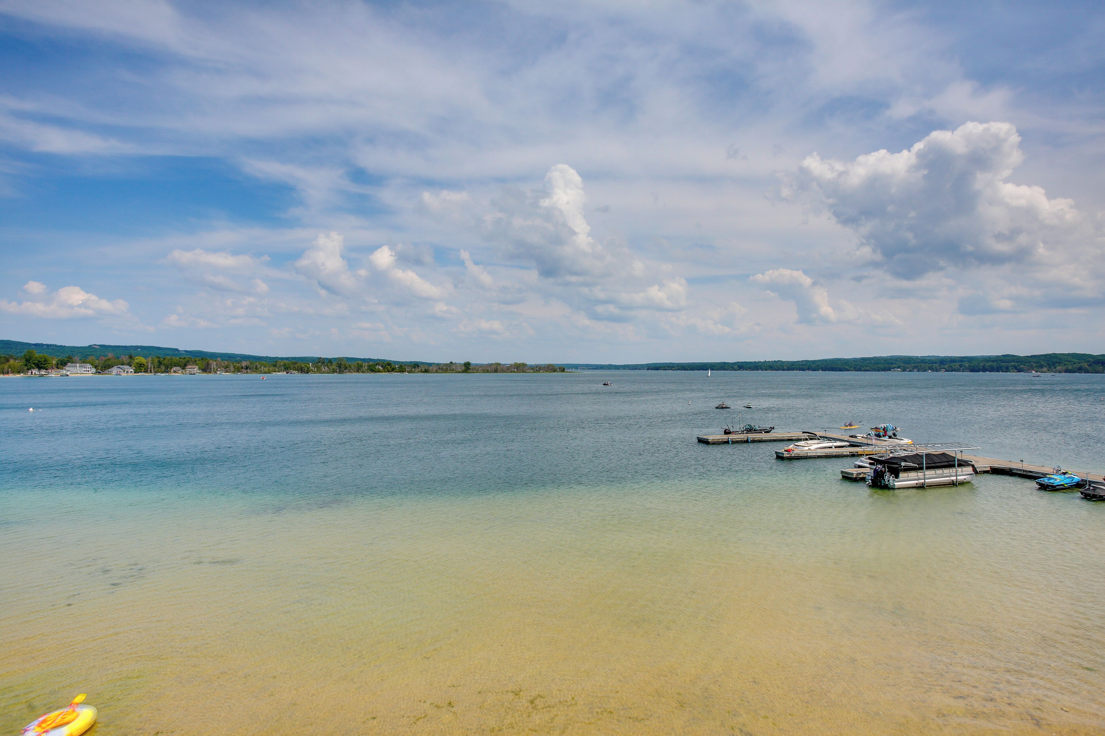 A calm lake with boats docked at the shore and a clear sky.