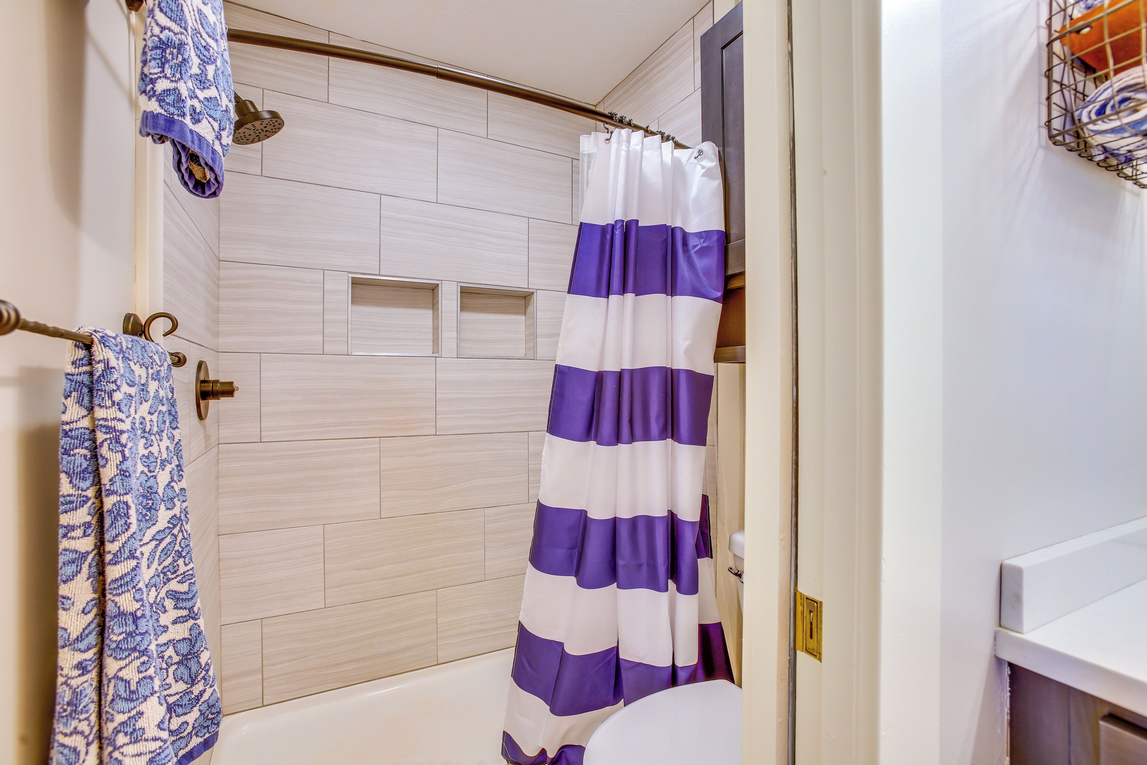 Une salle de bain avec un rideau de douche, des toilettes et un porte-serviettes.