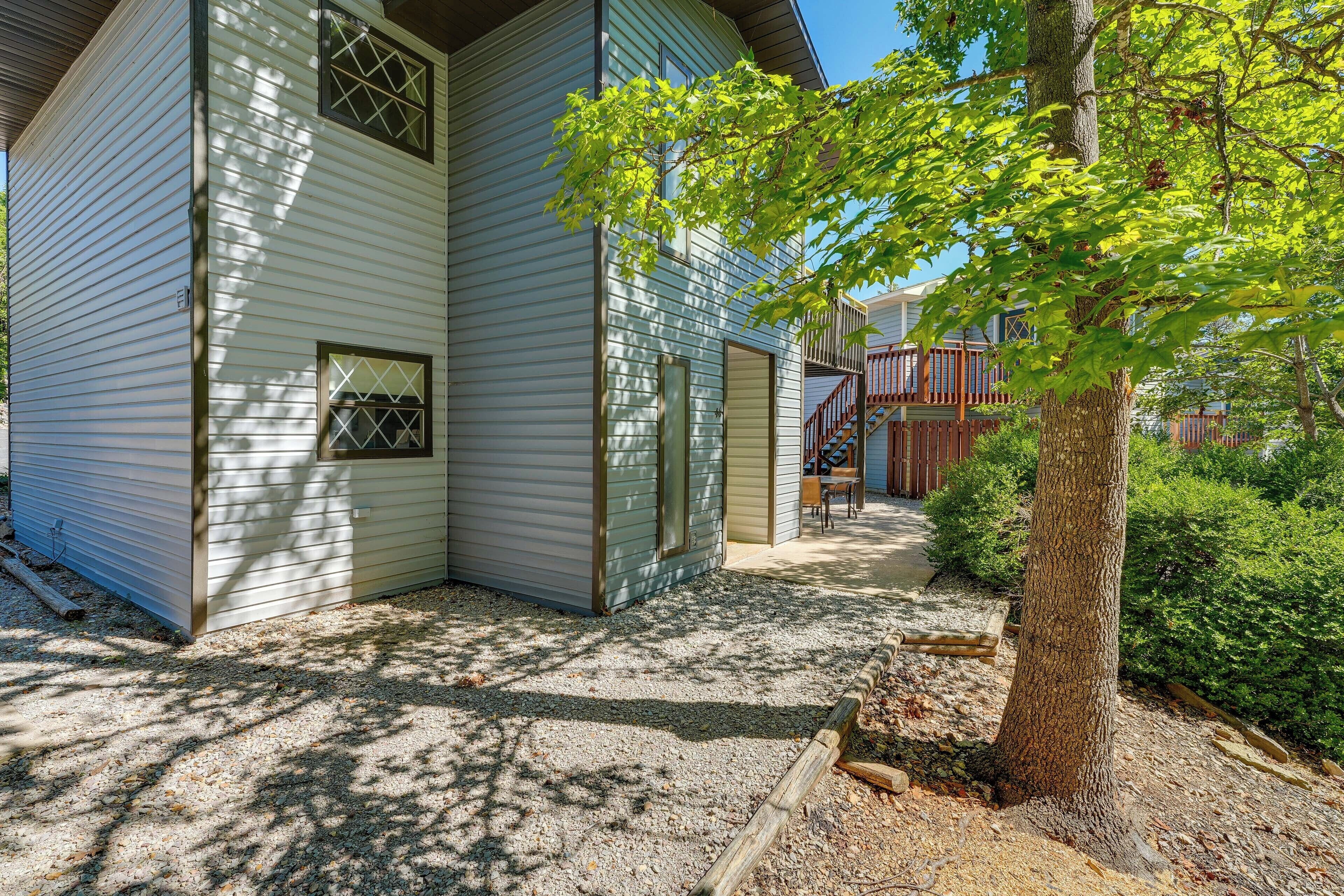 A two-story house with a gravel driveway and a tree in the foreground.