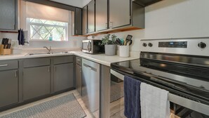 Een moderne keuken met roestvrijstalen apparatuur, grijze kastjes en een raam met zonwering.