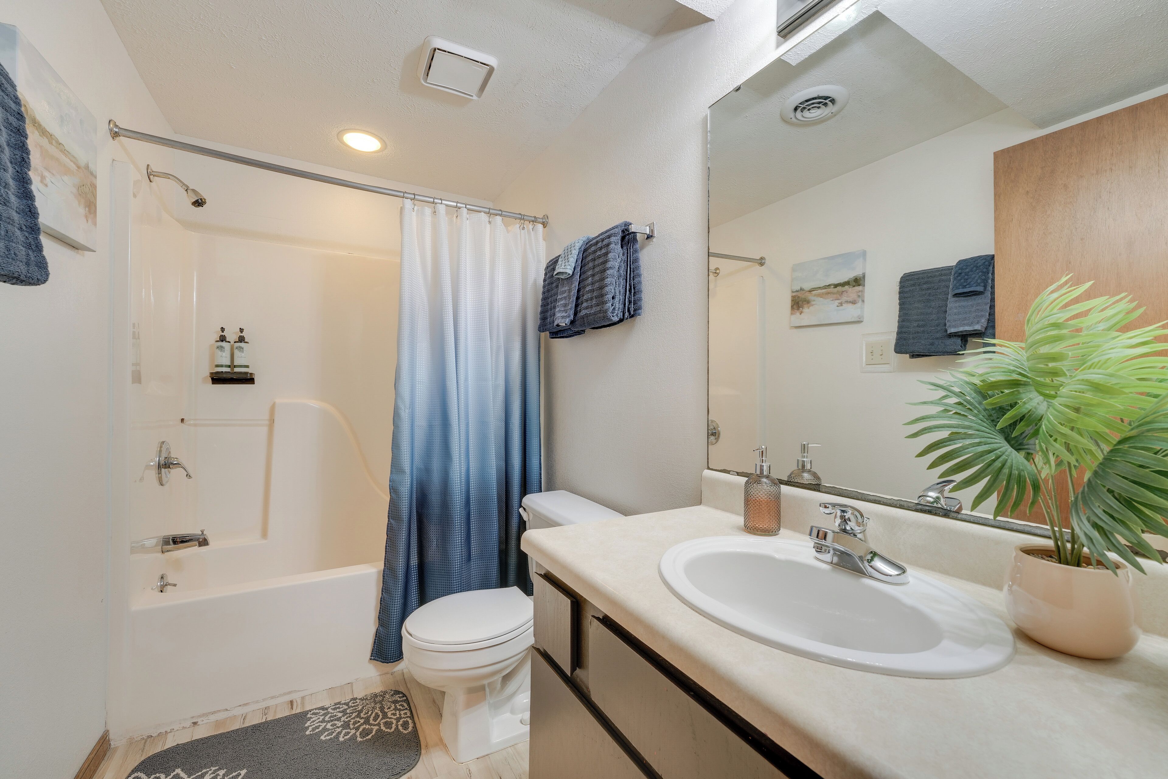 A modern bathroom with a bathtub, toilet, sink, and shower curtain.