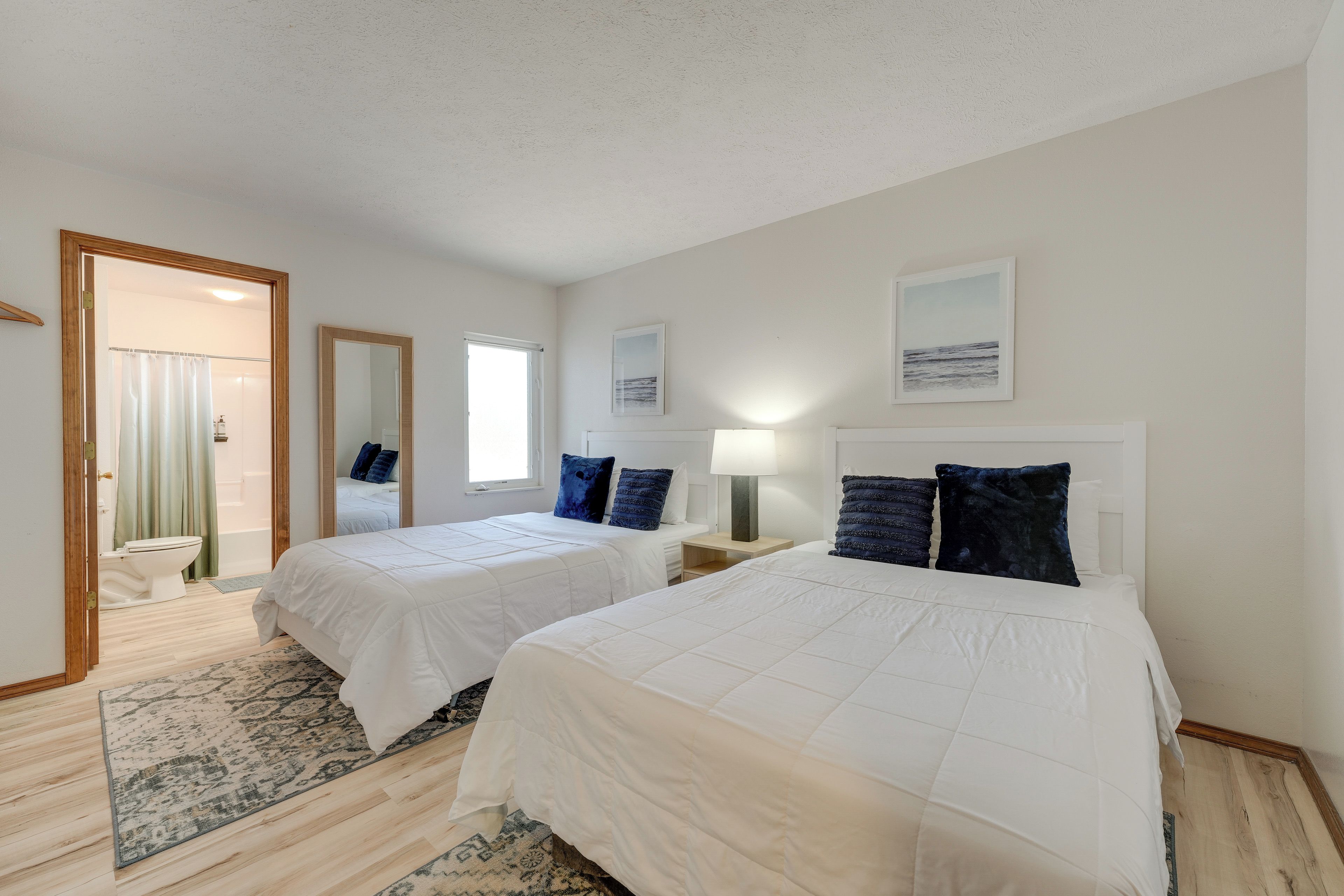Une chambre d’hôtel avec deux lits, une salle de bain et vue sur la mer.