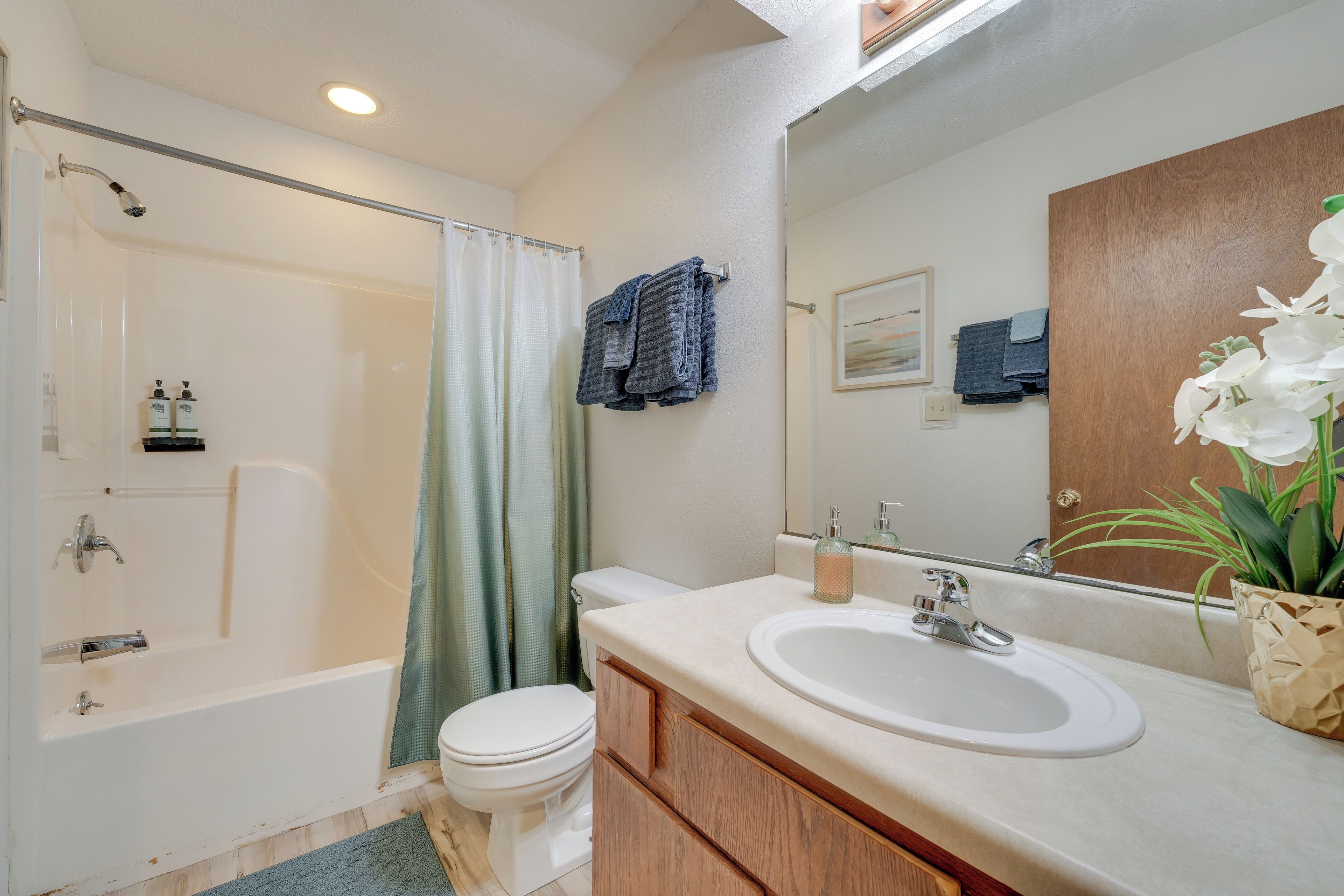 A bathroom with a bathtub, toilet, sink, and a large mirror.