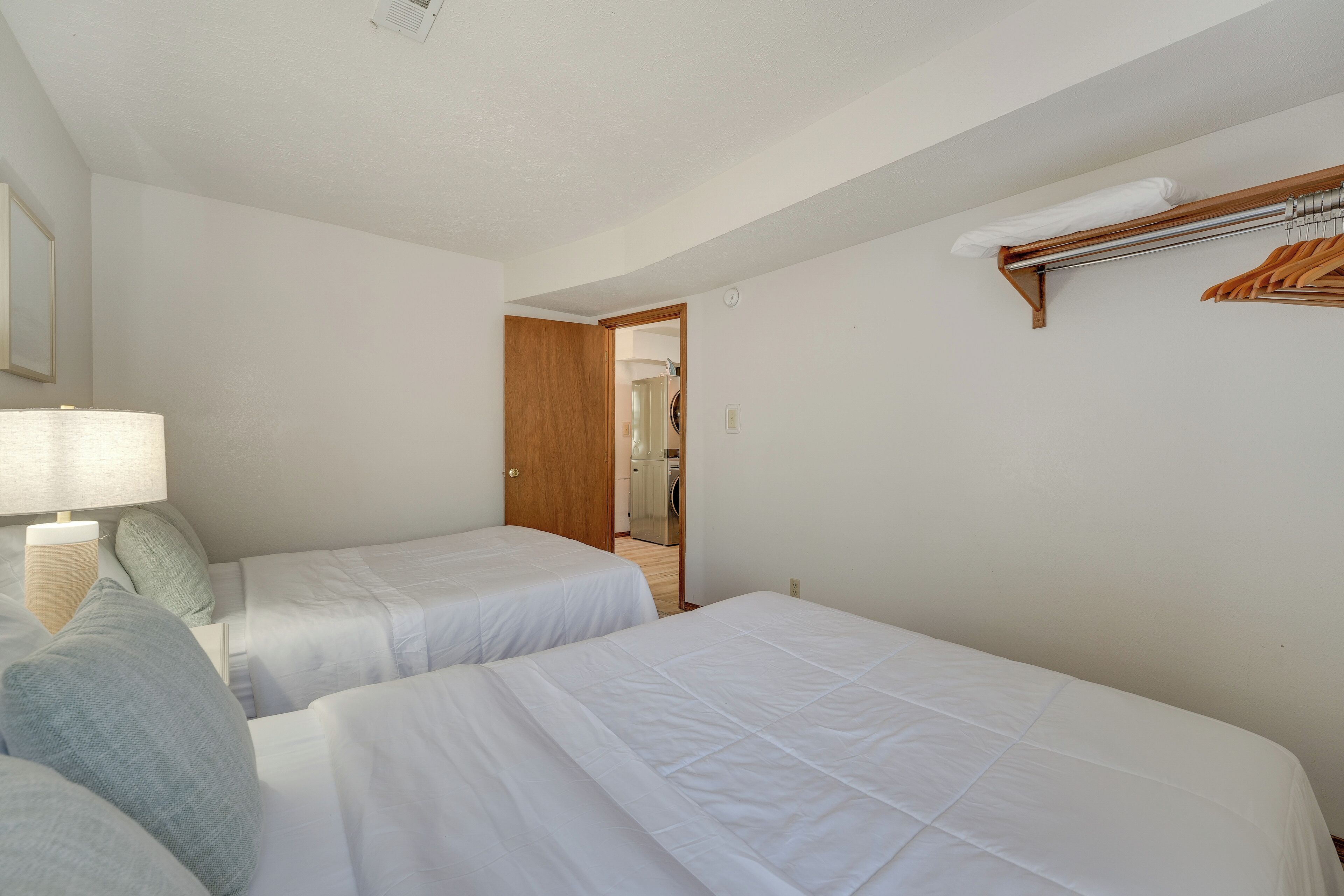Een hotelkamer met twee bedden, een houten deur, een spiegel en een handdoekrek.