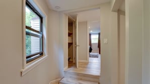 A hallway with wooden flooring, a closet with hanging clothes, and a door leading to another room. - Stylish Harveys Lake Apt - Steps to the Water! (Harveys Lake)
