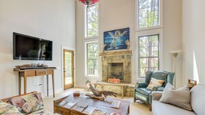 Un salón amplio con chimenea, un televisor grande y asientos cómodos.