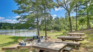 Zona de picnic junto al lago con bancos y sillas de madera, un pabellón y vistas al lago.