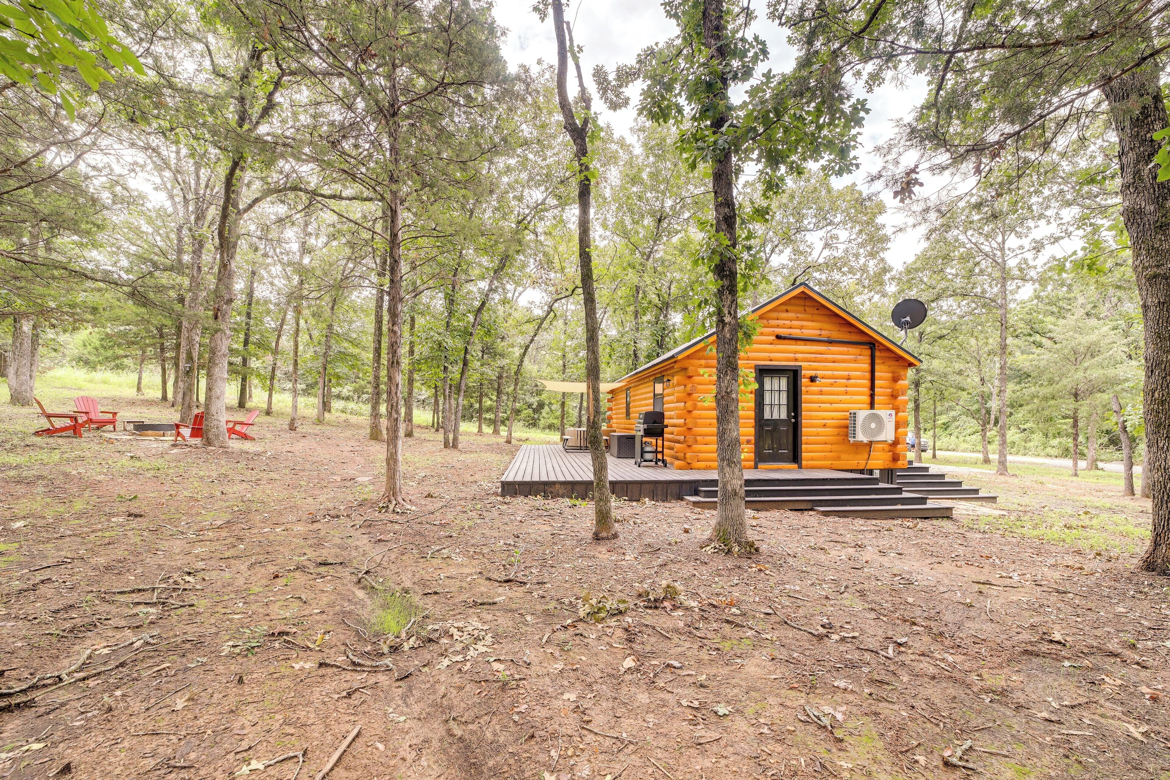 A log cabin with a deck, surrounded by trees.