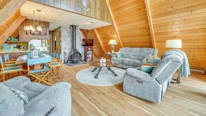 A cozy loft-style living room with a dining area, wooden ceiling beams, and a fireplace. - Long Lake Cabin w/ Kayaks, Private Beach & Dock! (Fountain)