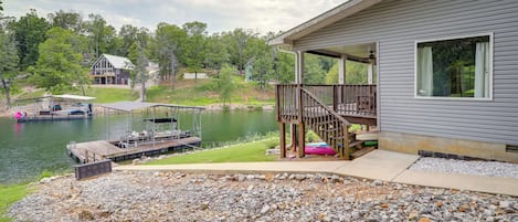 Une propriété au bord du lac, dotée d’un quai, d’une terrasse couverte et d’une maison avec une grande fenêtre.