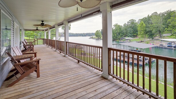 A wooden deck with chairs, a railing, and a view of a lake with boats. - Lakefront Horseshoe Bend Home w/ Boat Dock! (Horseshoe Bend)