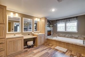 A spacious bathroom with a large vanity, double sinks, a bathtub, and a fireplace.