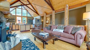 Un salon spacieux avec un plafond en bois, un grand canapé, une table basse et une cheminée.