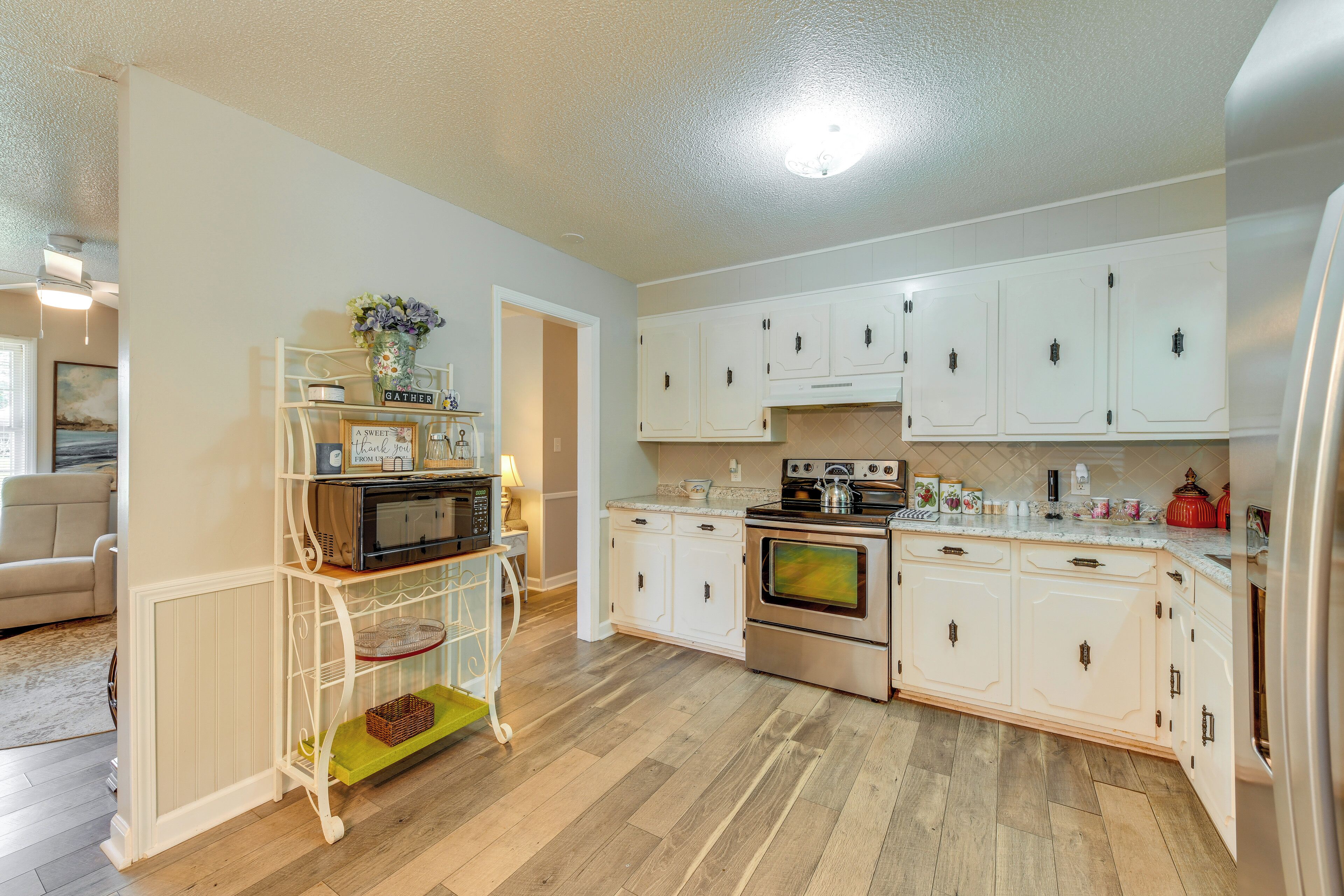 A kitchen with white cabinets, a stainless steel oven, and a microwave.