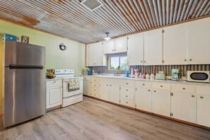A kitchen with a stainless steel refrigerator, white appliances, and wooden flooring. - Historic Home Near Table Rock Lake, Branson (Omaha)