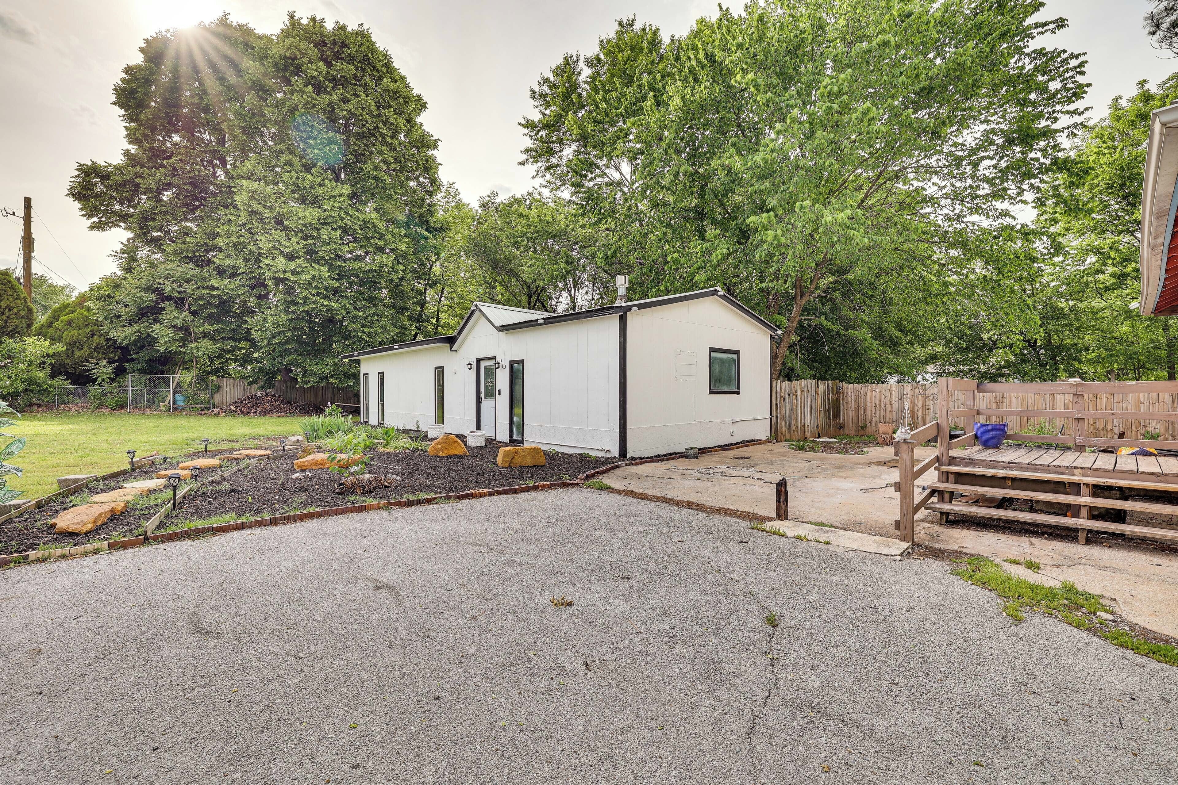 A small, single-story house with a gravel driveway and a wooden deck.