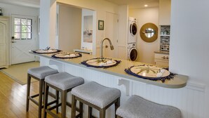 Una cocina con una isla central, taburetes de bar, un lavabo y una lavadora.