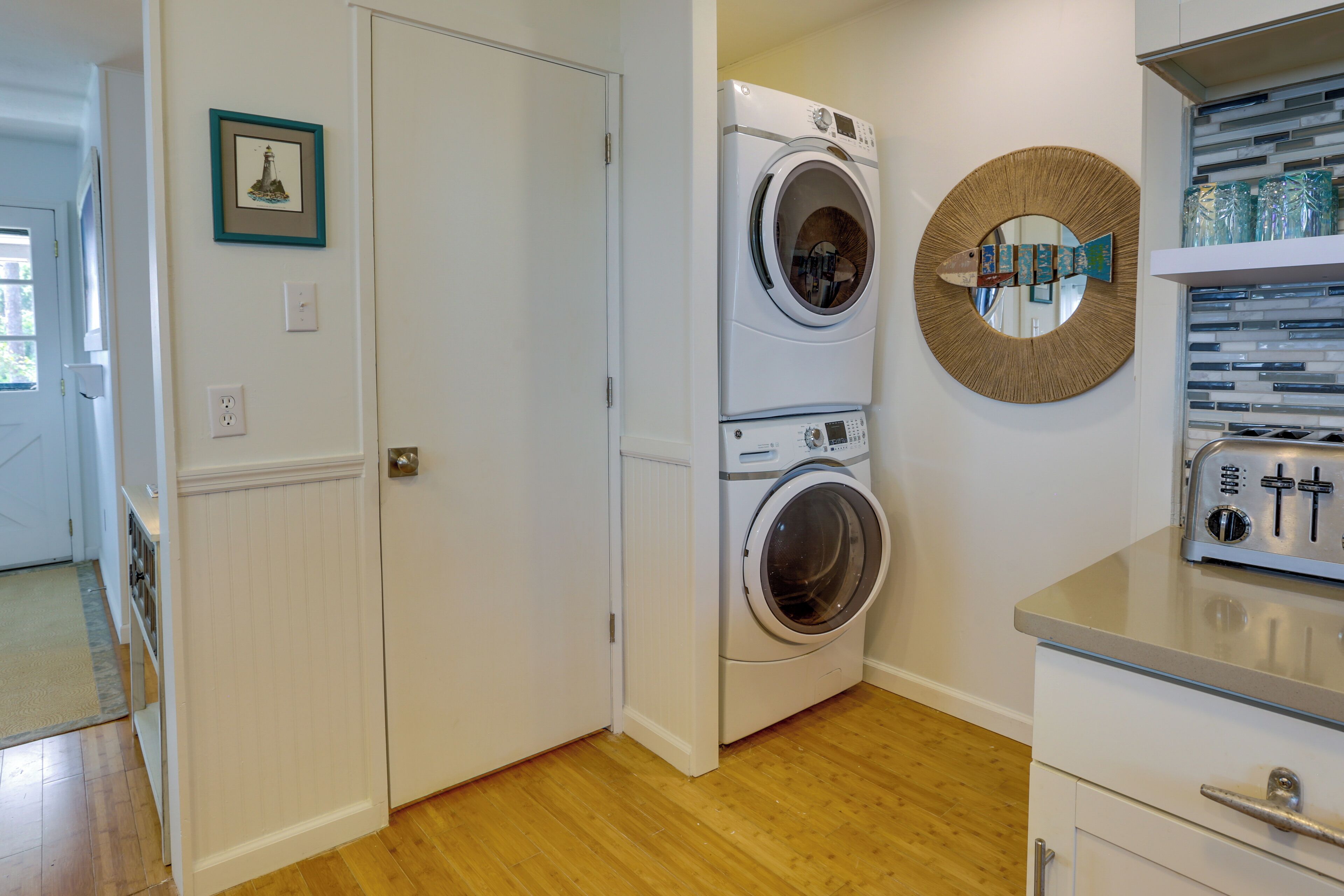 A laundry room with a washing machine, dryer, and a shelf with glass jars.