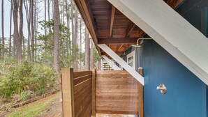 Una escalera de madera que lleva a un edificio azul con una puerta y un tirador metálico.