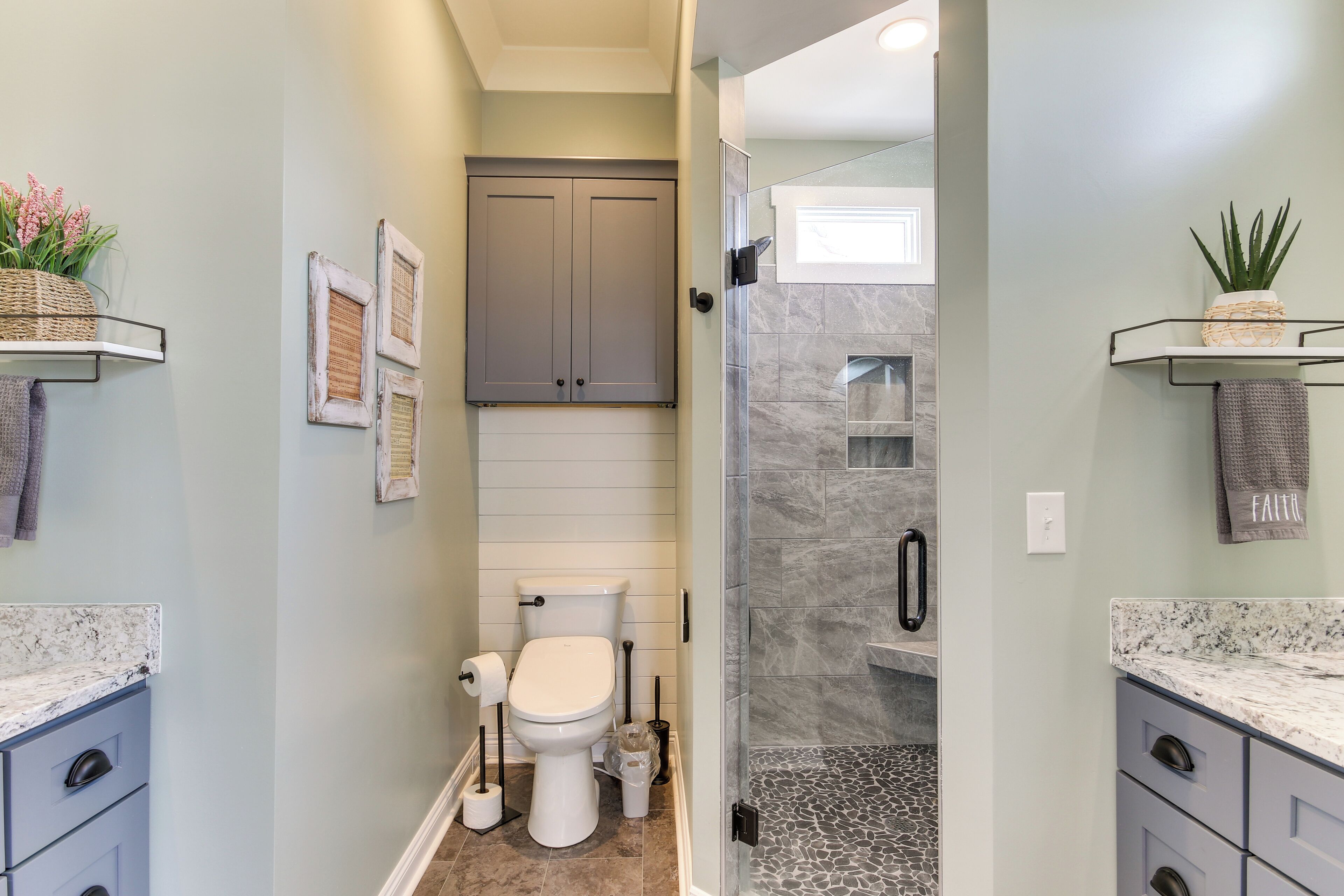Une salle de bain équipée de toilettes, d’une douche et de plans de travail en marbre.