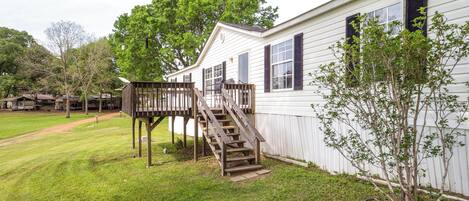 A white building with a wooden deck and stairs leading to a covered area.