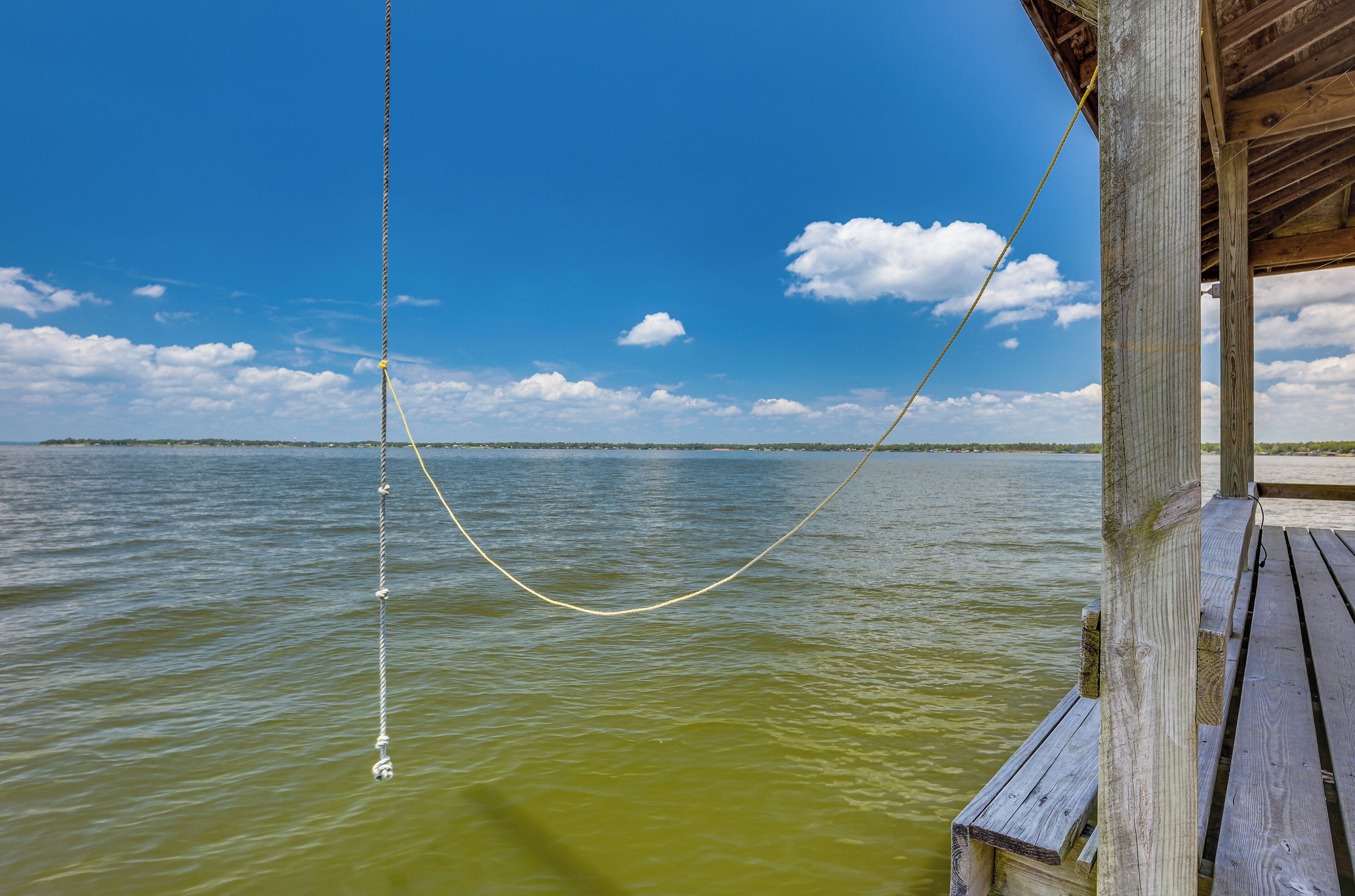 A wooden dock extending into a body of water with a clear sky and distant land.