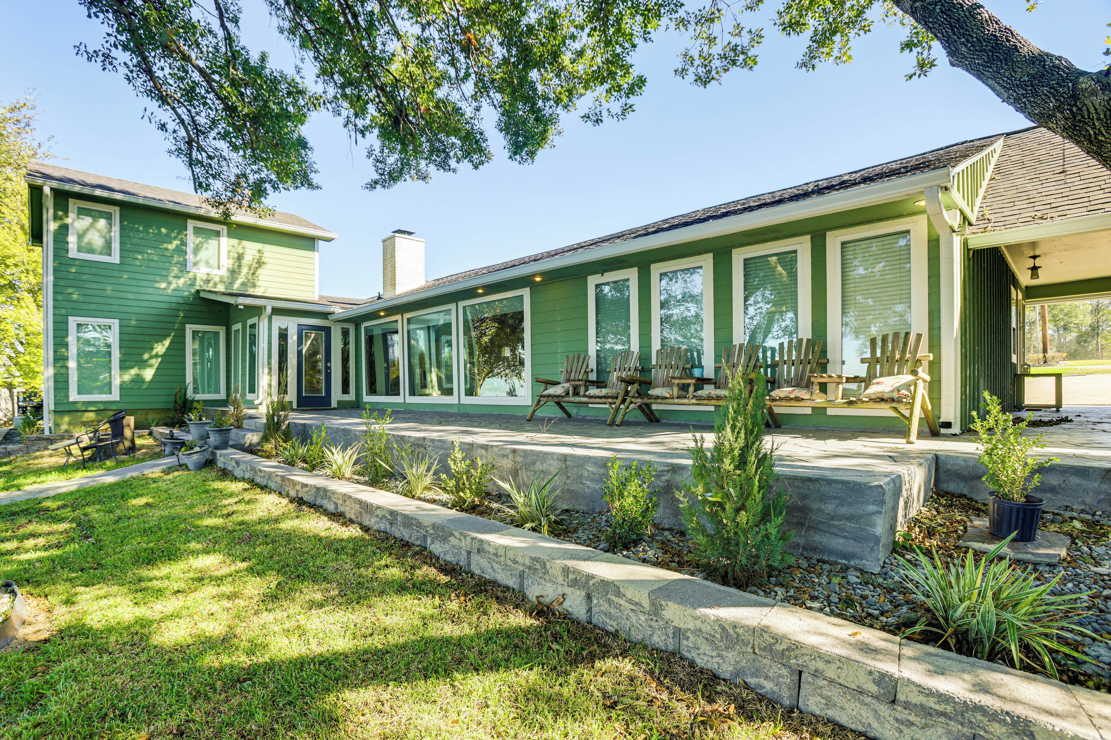 A green two-story house with a covered porch and outdoor seating.
