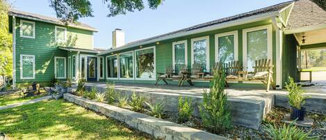 A green two-story house with a covered porch and outdoor seating.