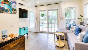 A modern living room with a sofa, a coffee table, and a teal cabinet. - Cozy Cottage: Minutes to Downtown Southport! (Southport)