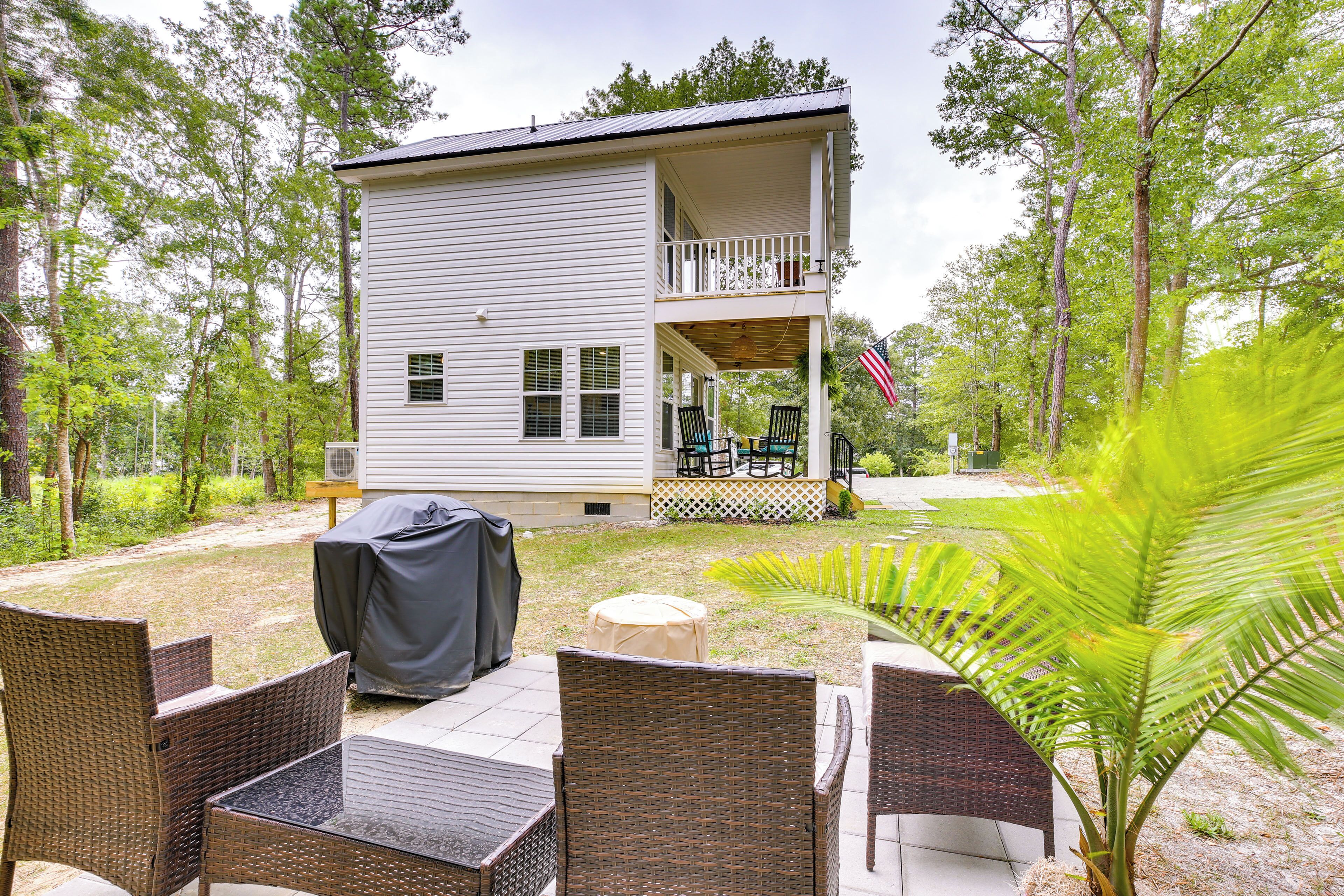 A two-story house with a covered patio area, outdoor furniture, and a small garden.