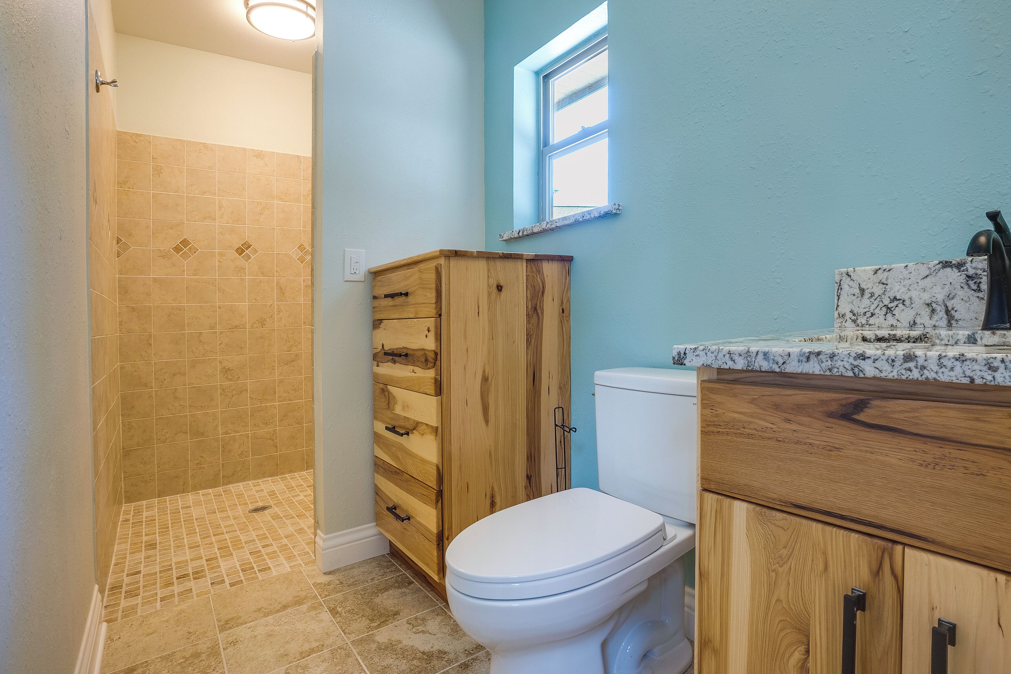 A bathroom with a shower, a toilet, and wooden cabinets.