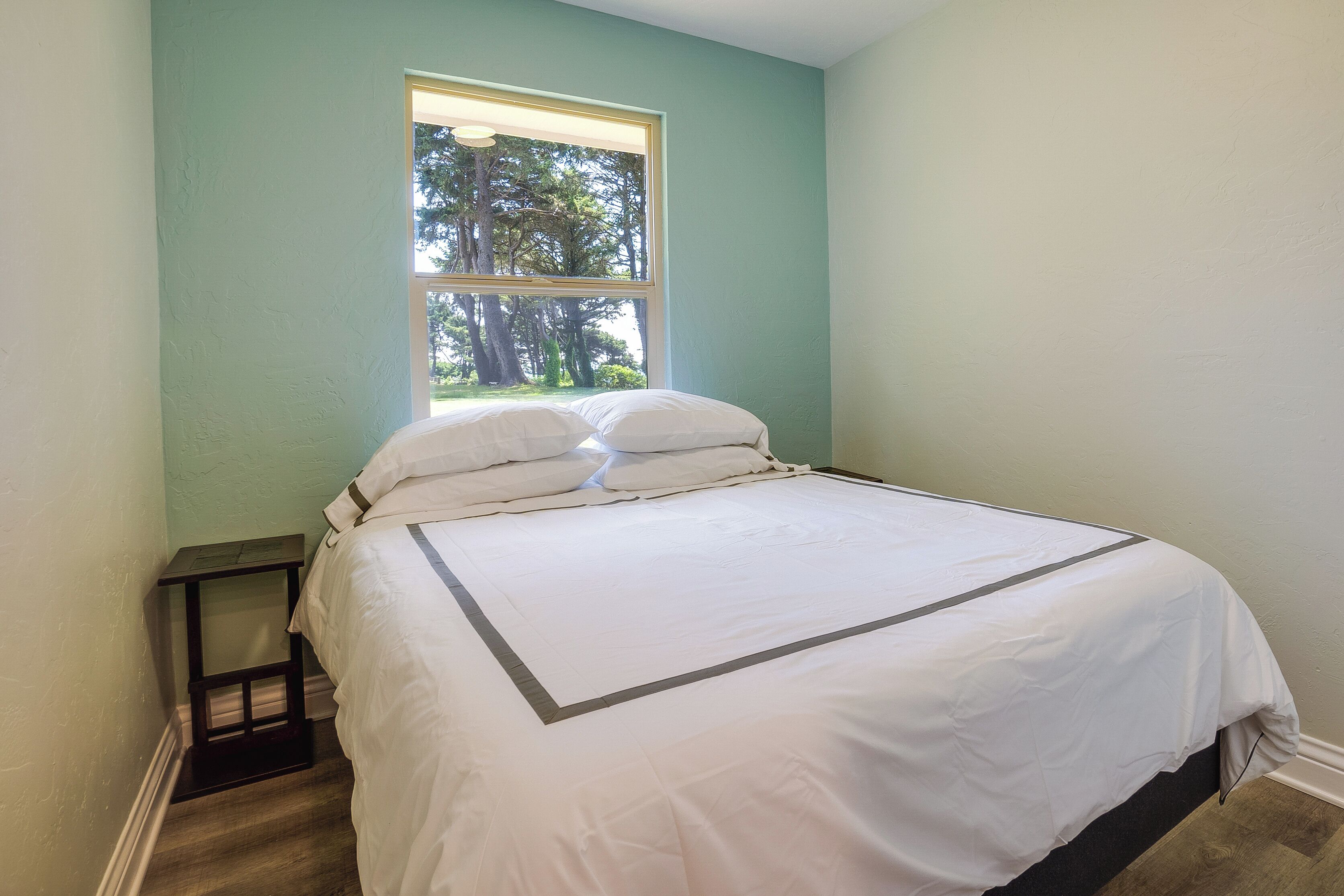 A bedroom with a bed, a window, and a nightstand.